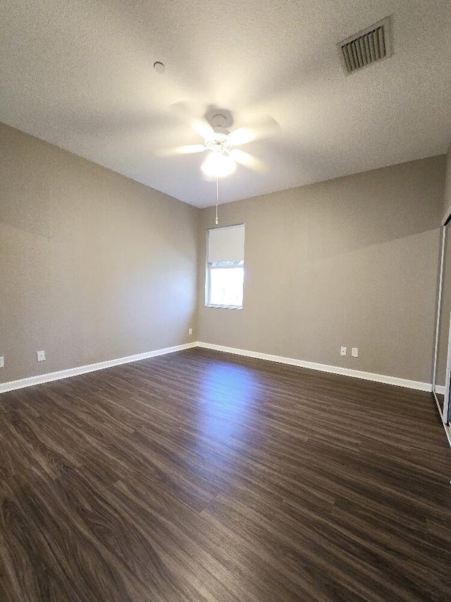 empty room featuring a textured ceiling, dark hardwood / wood-style floors, and ceiling fan