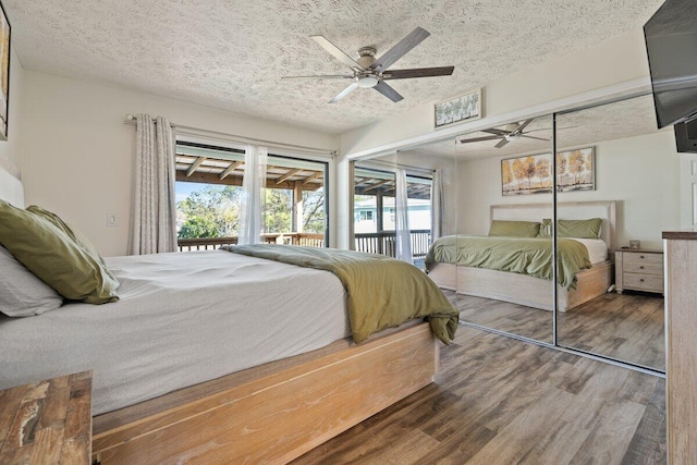 bedroom featuring a textured ceiling, access to outside, ceiling fan, hardwood / wood-style floors, and a closet