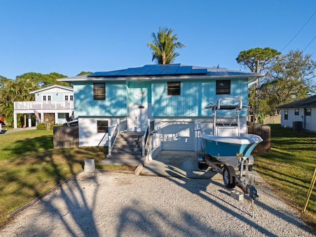 split foyer home featuring a front yard, solar panels, and a garage