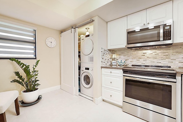 kitchen with backsplash, white cabinets, light tile patterned floors, stacked washer / drying machine, and stainless steel appliances