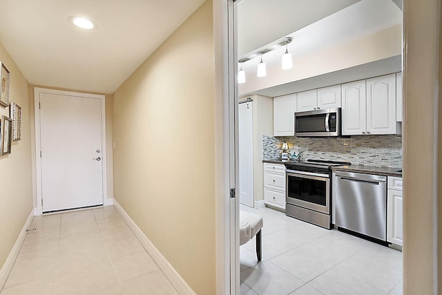 kitchen with white cabinets, light tile patterned floors, stainless steel appliances, and tasteful backsplash