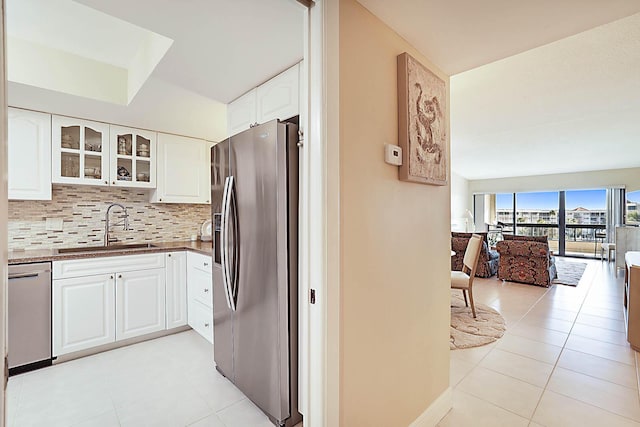 kitchen featuring white cabinetry, sink, stainless steel appliances, backsplash, and light tile patterned floors