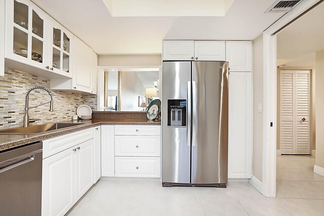 kitchen featuring decorative backsplash, appliances with stainless steel finishes, sink, light tile patterned floors, and white cabinets