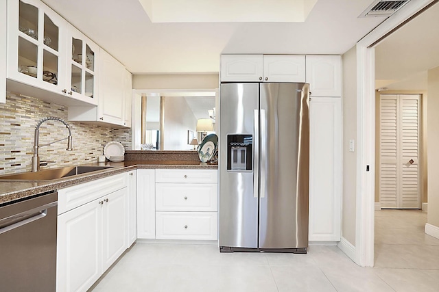 kitchen with backsplash, sink, light tile patterned floors, appliances with stainless steel finishes, and white cabinetry