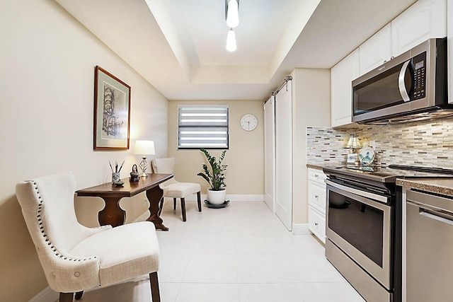 kitchen featuring stainless steel appliances, a raised ceiling, white cabinets, backsplash, and light tile patterned flooring