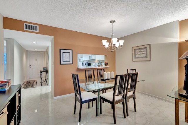 dining space featuring an inviting chandelier and a textured ceiling