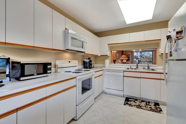 kitchen with white cabinets, sink, and white appliances