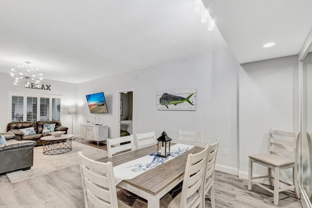 dining area with light hardwood / wood-style floors and a chandelier