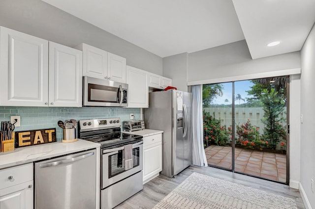 kitchen with light hardwood / wood-style flooring, stainless steel appliances, backsplash, and white cabinetry