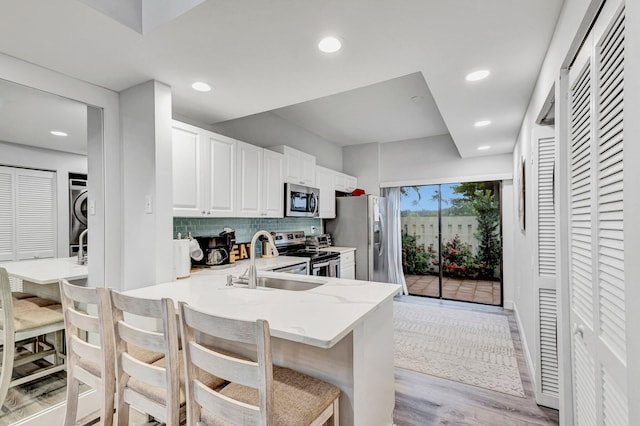 kitchen with a breakfast bar area, appliances with stainless steel finishes, kitchen peninsula, sink, and white cabinetry