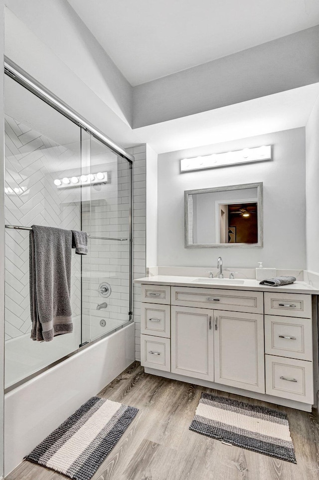 bathroom with wood-type flooring, vanity, and shower / bath combination with glass door