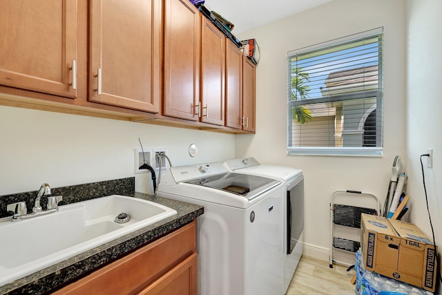 washroom featuring cabinets, sink, washer and dryer, and light hardwood / wood-style flooring