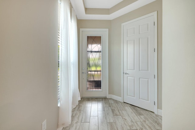 foyer entrance with light wood-type flooring and a tray ceiling