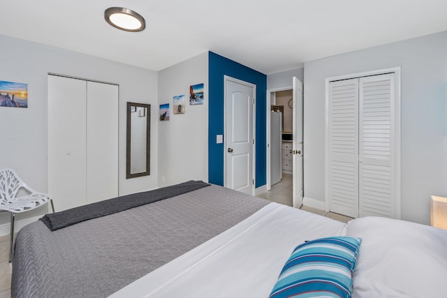 bedroom featuring light tile patterned floors and multiple closets