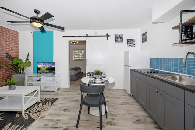 kitchen featuring gray cabinetry, a barn door, sink, and light hardwood / wood-style flooring