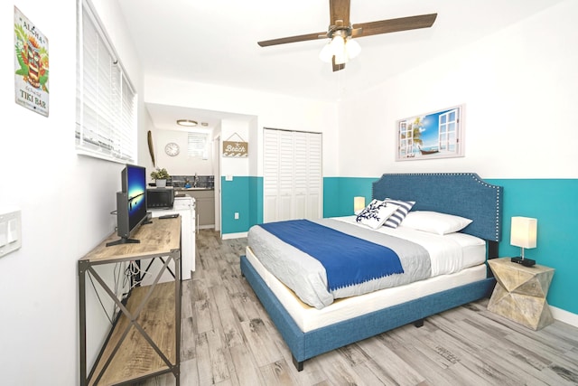 bedroom featuring light wood-type flooring, a closet, ceiling fan, and sink