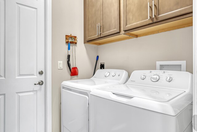 laundry room featuring washer and dryer and cabinets