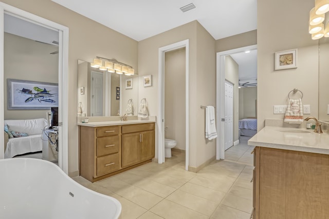 bathroom featuring a washtub, tile patterned flooring, vanity, and toilet