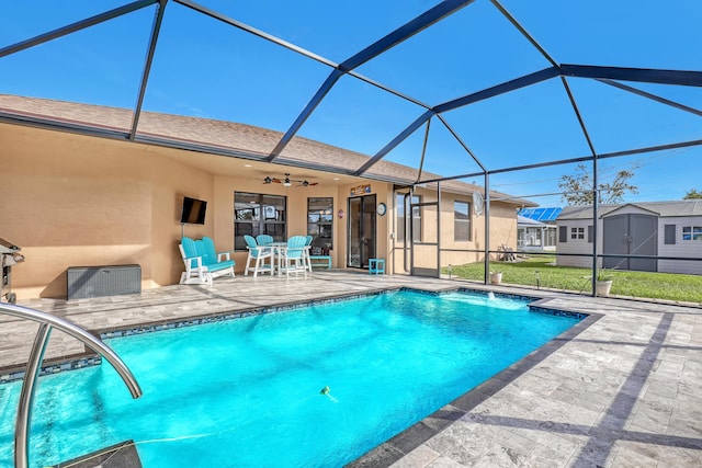 view of pool featuring a patio area, a storage shed, ceiling fan, and glass enclosure