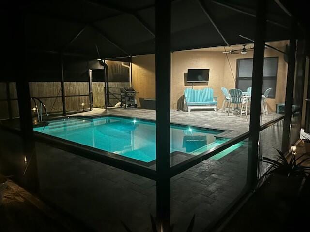 view of pool with ceiling fan, glass enclosure, and a patio