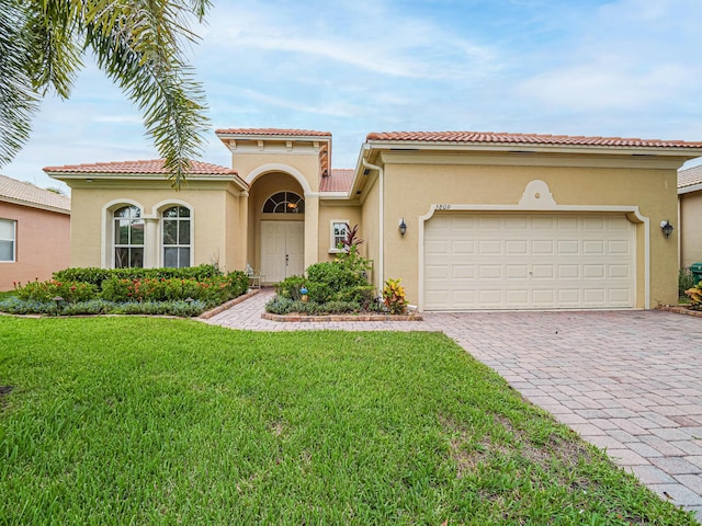 mediterranean / spanish-style house featuring a front yard and a garage