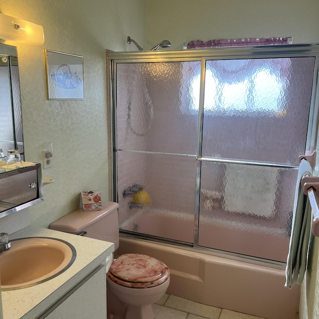 full bathroom featuring shower / bath combination with glass door, a textured wall, toilet, vanity, and tile patterned floors