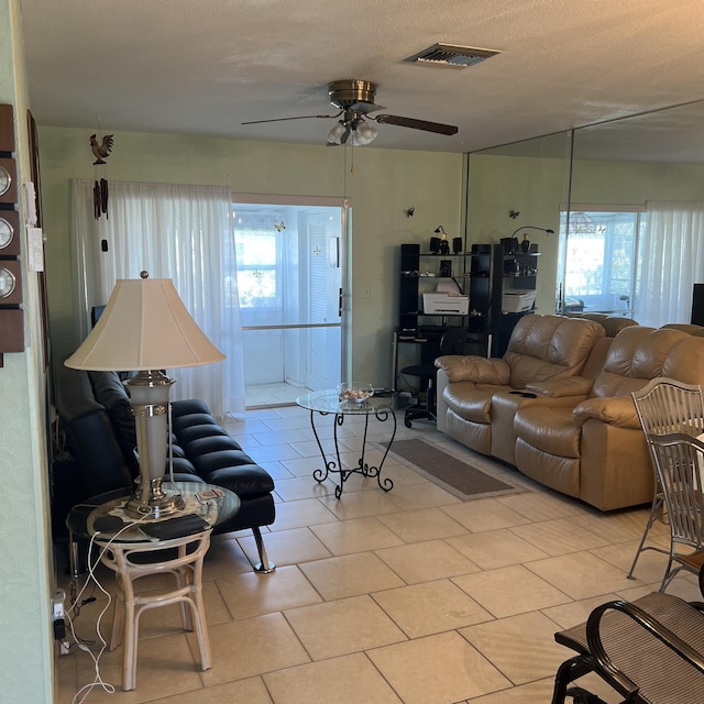 living area with light tile patterned floors, ceiling fan, a textured ceiling, and visible vents