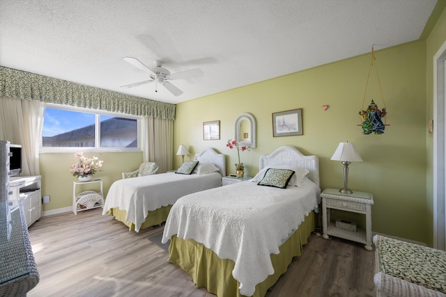 bedroom with ceiling fan, hardwood / wood-style floors, and a textured ceiling