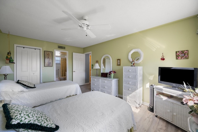 bedroom with ensuite bath, ceiling fan, a closet, and light wood-type flooring