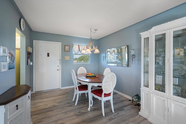 dining space with wood-type flooring and a notable chandelier