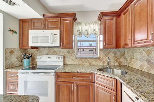 kitchen featuring light stone counters, white appliances, sink, and tasteful backsplash