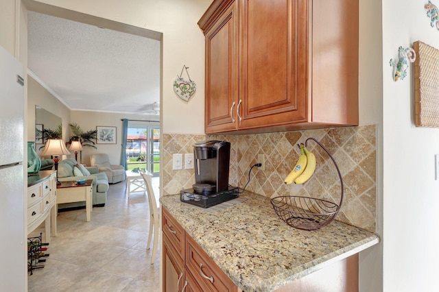 kitchen with decorative backsplash, light stone counters, light tile patterned flooring, and ornamental molding