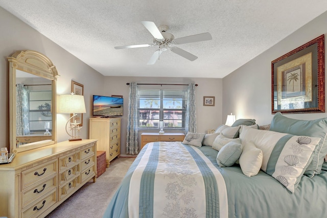 bedroom with ceiling fan, light carpet, and a textured ceiling