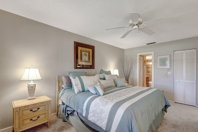 bedroom featuring light carpet, a closet, ceiling fan, and ensuite bathroom