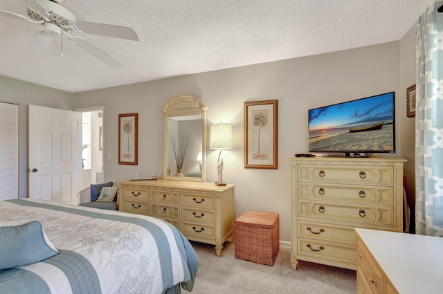 bedroom featuring a textured ceiling, light colored carpet, and ceiling fan