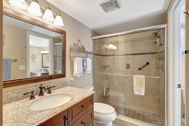 bathroom featuring vanity, toilet, and a shower with door