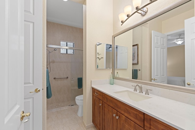 bathroom featuring toilet, tile patterned floors, tiled shower, and vanity