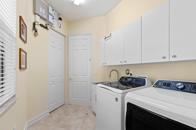 laundry area with washing machine and dryer, sink, a textured ceiling, light tile patterned floors, and cabinets