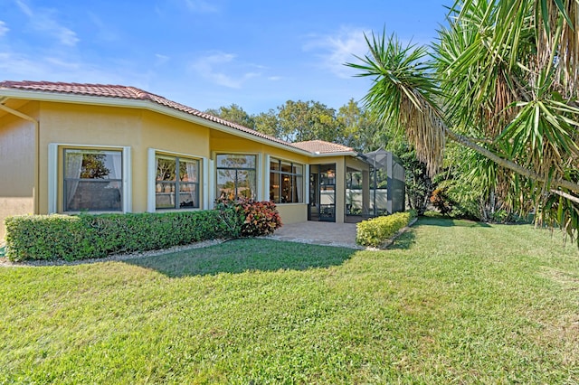 back of property featuring a lanai and a yard