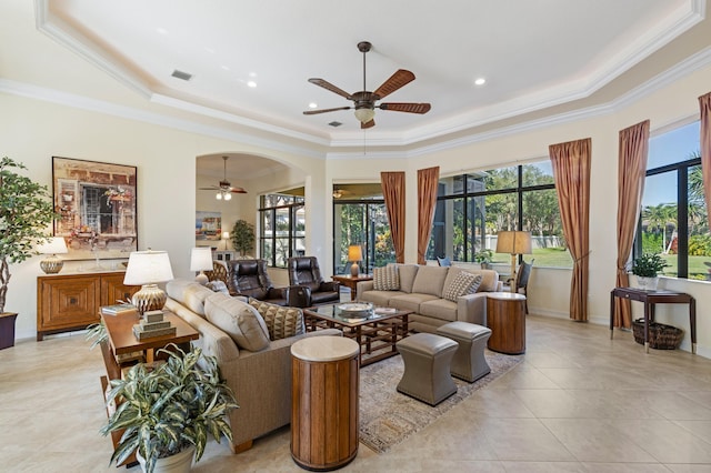 living room featuring a raised ceiling, light tile patterned floors, ceiling fan, and crown molding