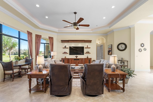 living room with a raised ceiling, ceiling fan, and crown molding