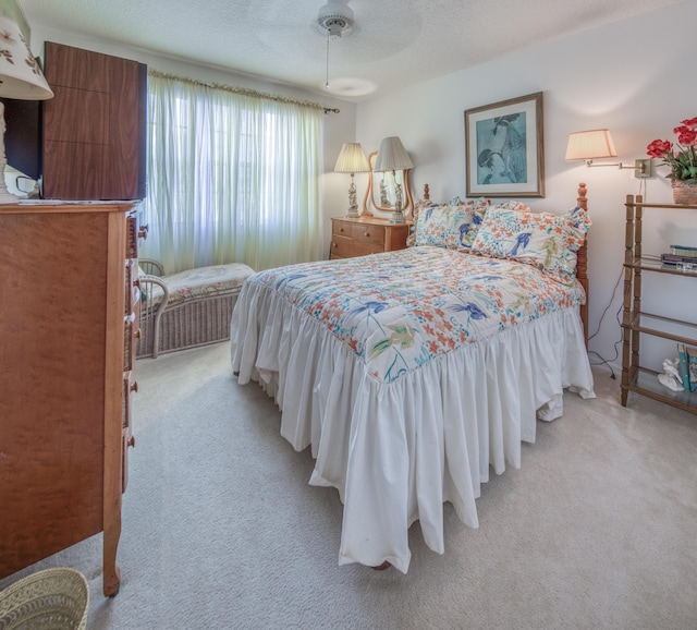 bedroom with ceiling fan, light carpet, and a textured ceiling