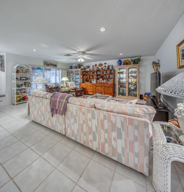 living room featuring ceiling fan, light tile patterned floors, and a textured ceiling