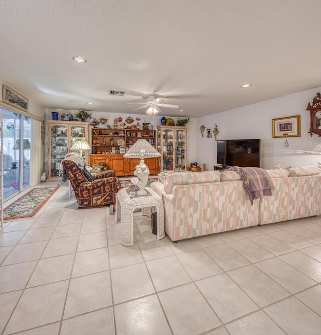 tiled living room featuring ceiling fan and a textured ceiling