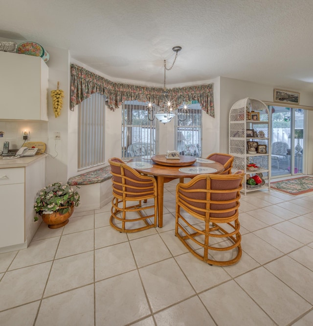 tiled dining room featuring a textured ceiling, a chandelier, and plenty of natural light