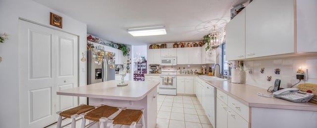 kitchen featuring a center island, white appliances, a kitchen breakfast bar, white cabinets, and sink