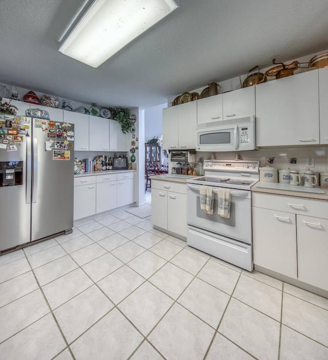 kitchen with white cabinets, light tile patterned floors, and white appliances