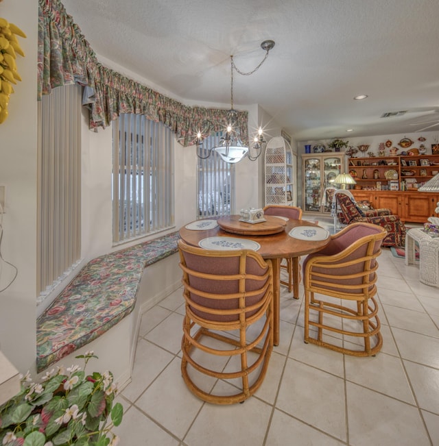 tiled dining space with an inviting chandelier and a textured ceiling