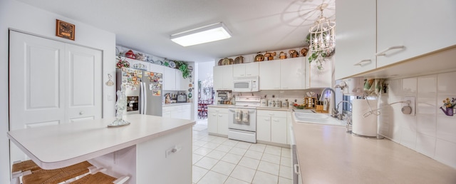 kitchen with sink, white appliances, white cabinetry, and pendant lighting