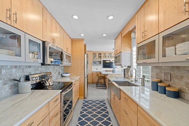 kitchen featuring stainless steel refrigerator with ice dispenser, a kitchen bar, light brown cabinetry, hanging light fixtures, and kitchen peninsula